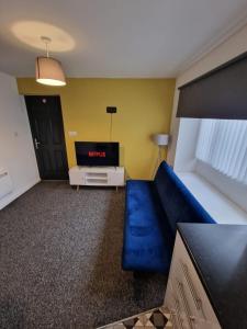 a living room with a blue couch and a tv at 1 bedroom Windy Nook -Great monthly offers in Sheriff Hill