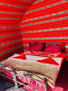 a bed in a room with a red wall at Wolf Trail Adventure in Wadi Rum