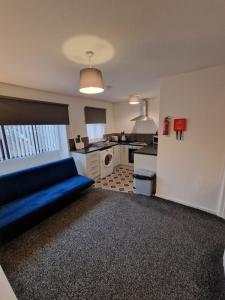 a living room with a blue couch and a kitchen at 1 bedroom Windy Nook -Great monthly offers in Sheriff Hill