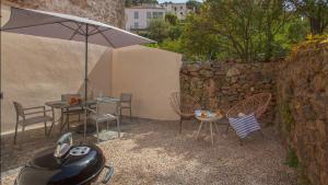 une terrasse avec un parasol, une table et des chaises dans l'établissement Casa Anto - Au coeur de Calenzana, à Calenzana