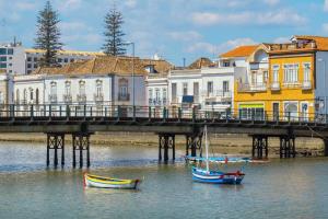 un pont avec des bateaux dans l'eau à côté des bâtiments dans l'établissement Villa Figo, à Luz de Tavira