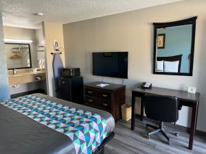 Habitación de hotel con cama, escritorio y TV. en Kansas Inn, en Independence