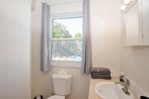 ein Bad mit einem WC, einem Waschbecken und einem Fenster in der Unterkunft OceanBliss: Exuma, Waterfront sleeps 8 in Michelson