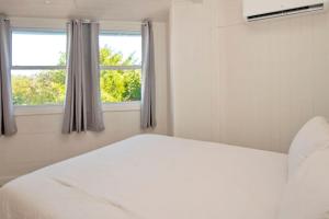 a bedroom with a white bed and two windows at OceanBliss: Exuma, Waterfront sleeps 8 in Michelson