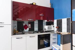 cocina con armarios rojos y microondas en Click Center Apartment, en Catania