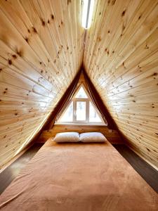 a large bed in a wooden room with a window at Dolinka Lodge in Dzhergalan