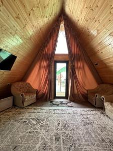 a attic room with a large window and two chairs at Dolinka Lodge in Dzhergalan