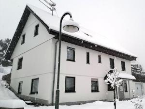 een met sneeuw bedekt gebouw met een straatlicht bij Ferienwohnungen Seelenglück in Oberdrackenstein