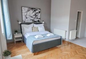 a bedroom with a large bed with blue sheets and white pillows at Mikszáth Apartments Budapest in Budapest