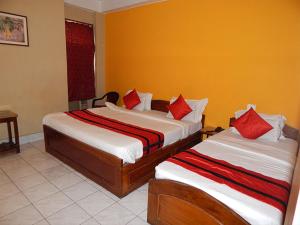 two beds in a hotel room with red pillows at HOTEL BREEZE NEW JALPAIGURI in Siliguri