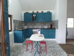 uma cozinha com armários azuis e uma mesa e bancos em La MARTELLERIE em Berville-sur-Seine