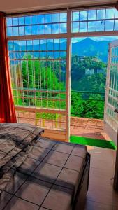 a bedroom with a large window with a view at The Himalaya Retreat Resort, Experience Nature in the Lap of Himalayas in Mussoorie
