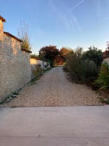 an empty road with a brick wall and trees at Hotel Karina in Jarnac