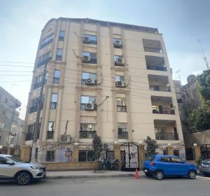 Misr Al Jadedah في القاهرة: مبنى طويل وبه سيارات متوقفة أمامه