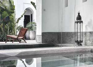 a chair and a lamp next to a swimming pool at Riad Atay in Marrakesh