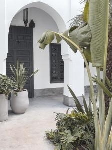 a courtyard with potted plants and a black door at Riad Atay in Marrakech