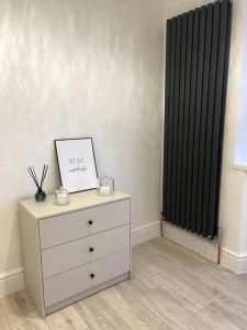 a dresser with a picture on it next to a window at Stylish King Size Room in Modern Renovated House in Catford