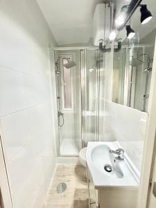 baño blanco con ducha y lavamanos en Centro Ronda de Segovia Aparment, en Madrid