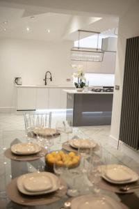 uma cozinha com uma mesa com pratos e copos em Stylish King Size Room in Modern Renovated House em Catford
