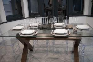 uma mesa de vidro com cadeiras, pratos e copos de vinho em Stylish King Size Room in Modern Renovated House em Catford