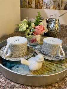 a table with two cups and plates and a bird figurine at Confortable apartamento- Cotuí in Cotuí