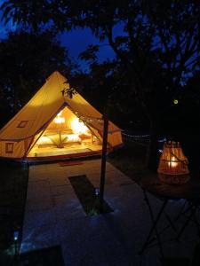 a tent is lit up in the dark at Tente mongole " ô Rêves Atypiques" in Boucé