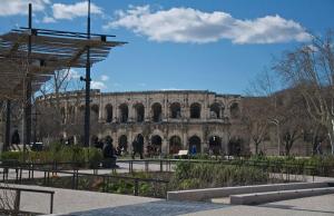 ein Gebäude in einem Park mit einem Gebäude im Hintergrund in der Unterkunft Les Copains d'Abord in Nîmes