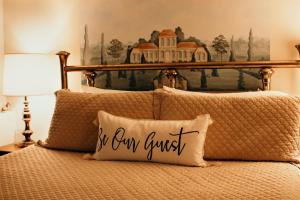 a bed with a pillow with the words be our own guest at The Richard Johnston Inn & 1890 Caroline House in Fredericksburg