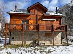 a large wooden house with a deck in the snow at Chalet bois au coeur des Pyrénées ariégeoises in LʼHospitalet-près-lʼAndorre