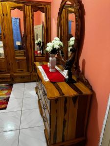 a dressing table with a mirror and a vase of flowers at Cocklestop Inn, Jamaica in Pond Side