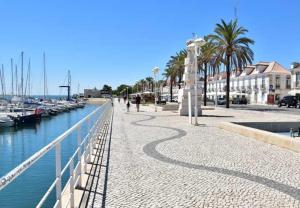 una pasarela junto a un puerto deportivo con barcos en O Encanto da Vila, en Vila Real de Santo António