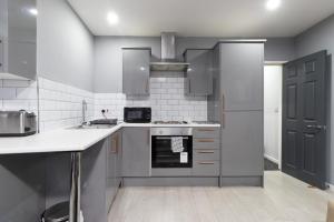 a kitchen with stainless steel appliances and gray cabinets at Central 2 Bed flat in City Centre with Ensuites and Workspaces in Coventry