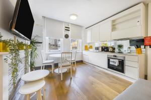eine Küche mit weißen Schränken sowie einem Tisch und Stühlen in der Unterkunft Modern one bedroom in Fitzrovia, Central London in London