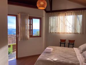 a bedroom with a bed and two chairs and windows at Pouso Lumiar in Lavras Novas