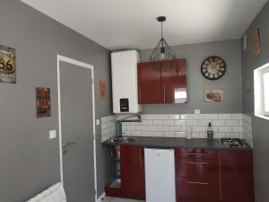 a kitchen with red cabinets and a sink at studio avec terrasse "Le Loup" in Lamotte-Beuvron