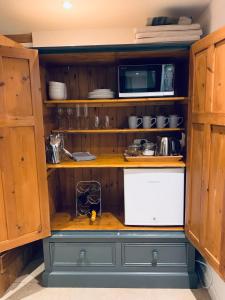 eine Küche mit einer Theke, einer Mikrowelle und einem Kühlschrank in der Unterkunft 2 Beds & living in our idyllic country Cottage in Bedford