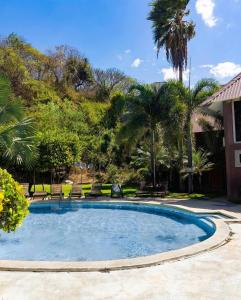 una piscina en un patio con palmeras en Punta Mango Surf Resort, en Jucuarán