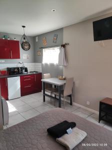 a kitchen with red cabinets and a table in a room at studio avec terrasse "Le Loup" in Lamotte-Beuvron