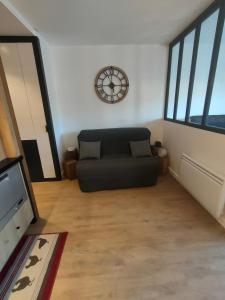 uma sala de estar com um sofá e um relógio na parede em Magnifique 3 étoiles en hyper centre avec place privée em Aix-les-Bains
