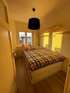 ein kleines Schlafzimmer mit einem Bett mit einer karierten Decke in der Unterkunft Lovely 2-bedroom apartment with balcony (near center) in Maastricht