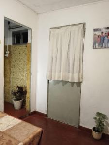 Zimmer mit einer Tür und einem Fenster mit einem Vorhang in der Unterkunft "Mi pequeño refugio" - Apartamento Colonia del Sacramento in Colonia del Sacramento