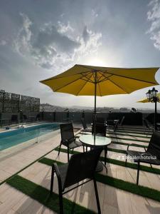 uma mesa e cadeiras com um guarda-sol ao lado de uma piscina em بالم السكنية em Abha