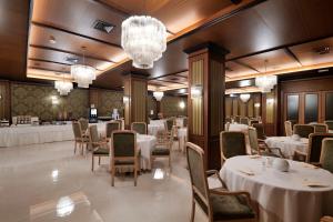 un comedor con mesas y sillas blancas y lámparas de araña en Hotel Delle Palme, en Lecce