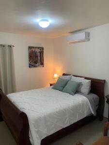 Schlafzimmer mit einem Bett mit weißer Bettwäsche und blauen Kissen in der Unterkunft Home in Ensenada close to beach in Ensenada