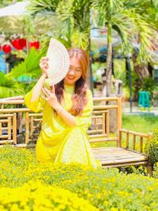 uma mulher sentada num banco a segurar um chapéu em Hồ Cốc Park & Resort em Xã Như Lâm