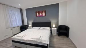 - une chambre avec un grand lit blanc et une chaise dans l'établissement CT Apartment Wurzen, à Wurzen