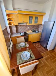a kitchen with a wooden table and a refrigerator at Apartment SUNSET in Subotica