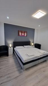 a bedroom with a large bed and two chairs at CT Apartment Wurzen in Wurzen