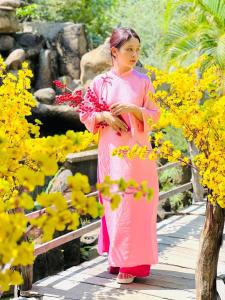 uma mulher num vestido rosa segurando flores em Hồ Cốc Park & Resort em Xã Như Lâm