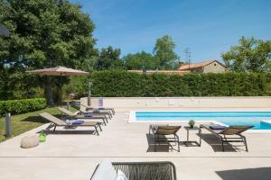 a swimming pool with lounge chairs and an umbrella at VILLA DEL SOL in Labin